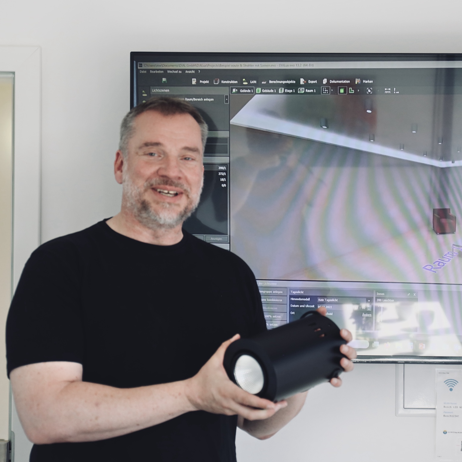 Michael Wollbrück mit einem schwarzen LED-Strahler vor einer Lichtplanung